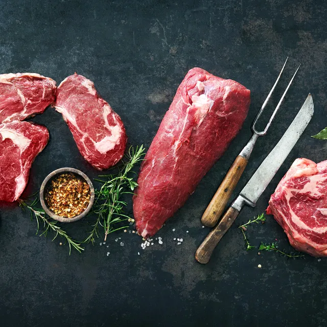 Fleisch auf Steintafel mit Gewürzen und Besteck